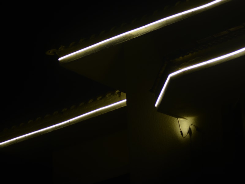 Permanent exterior LED lighting installed along roofline of home at night